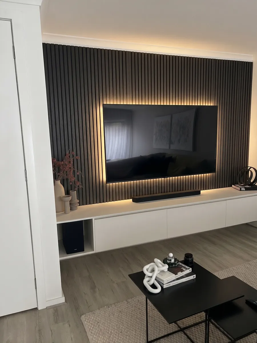 Charcoal timber slat feature wall with LED backlighting behind the TV in a Melbourne lounge