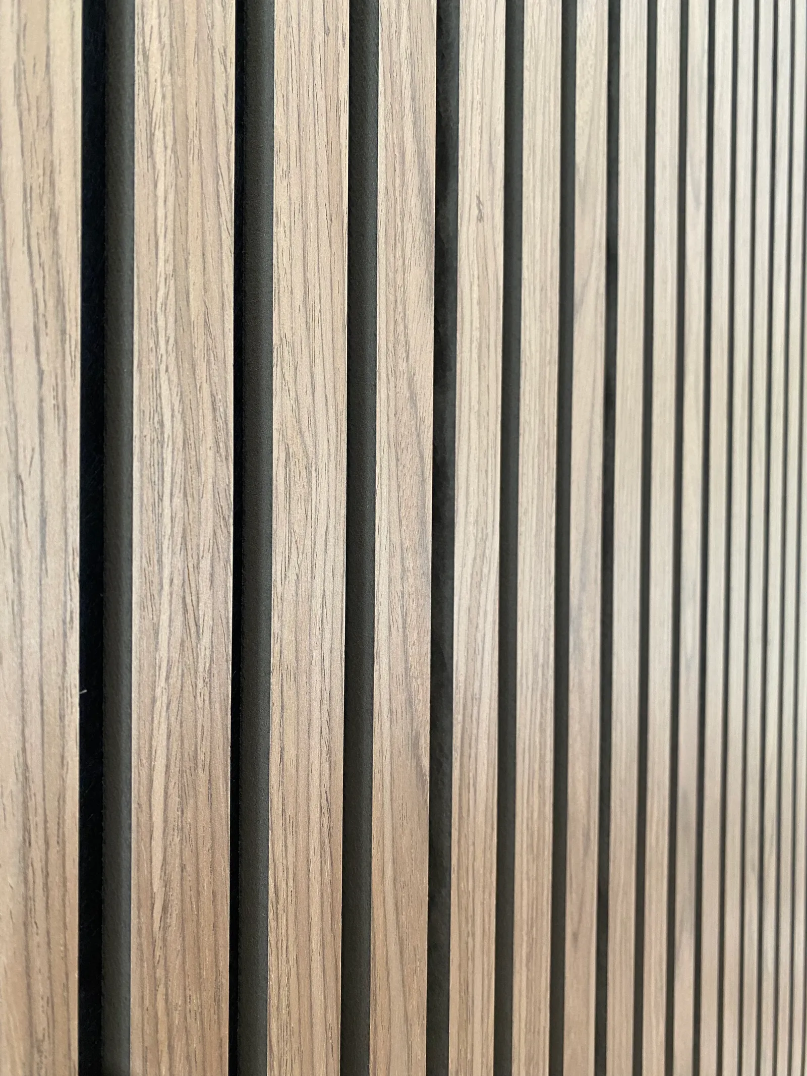 Close-up of natural oak timber slats and their black acoustic felt backing on an installed feature wall